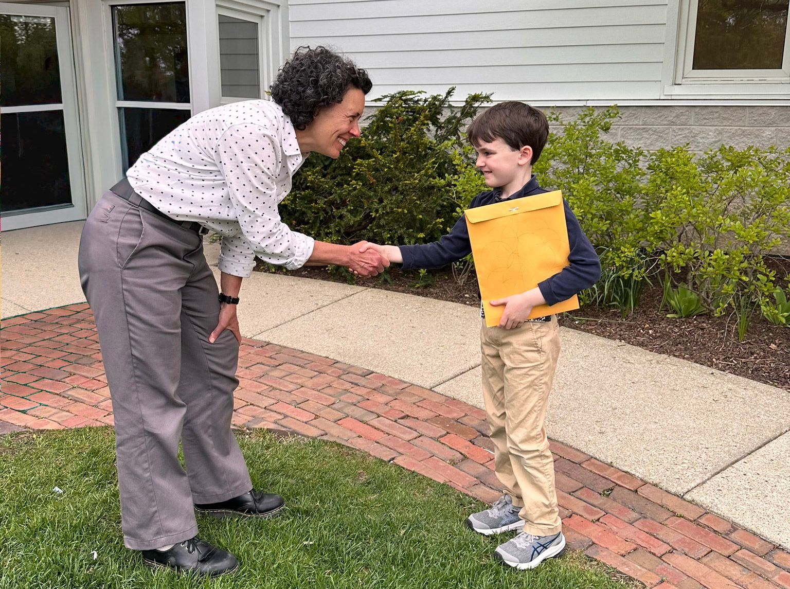 A teacher and Montessori student at Forest Bluff School in Lake Bluff, IL, shake hands.