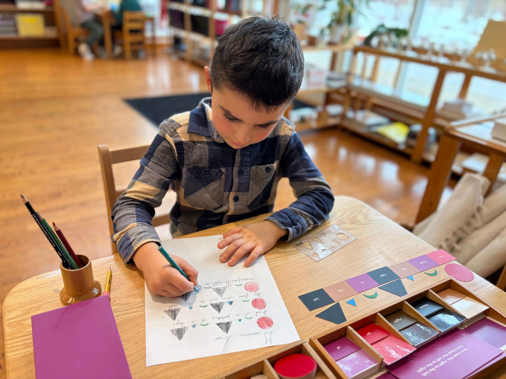 A Montessori student at Forest Bluff School uses grammar symbols and color-coded tiles
