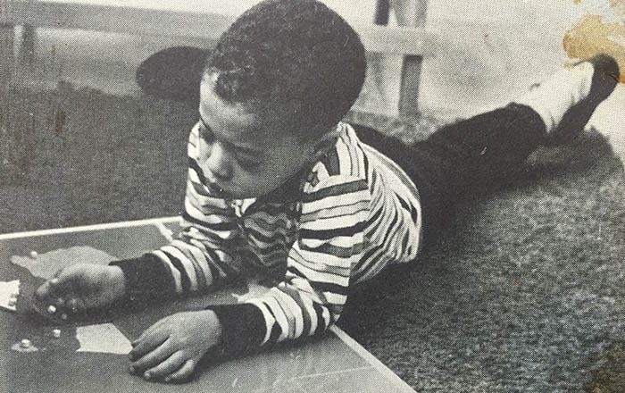 A young boy is laying on the floor working with a Montessori map puzzle