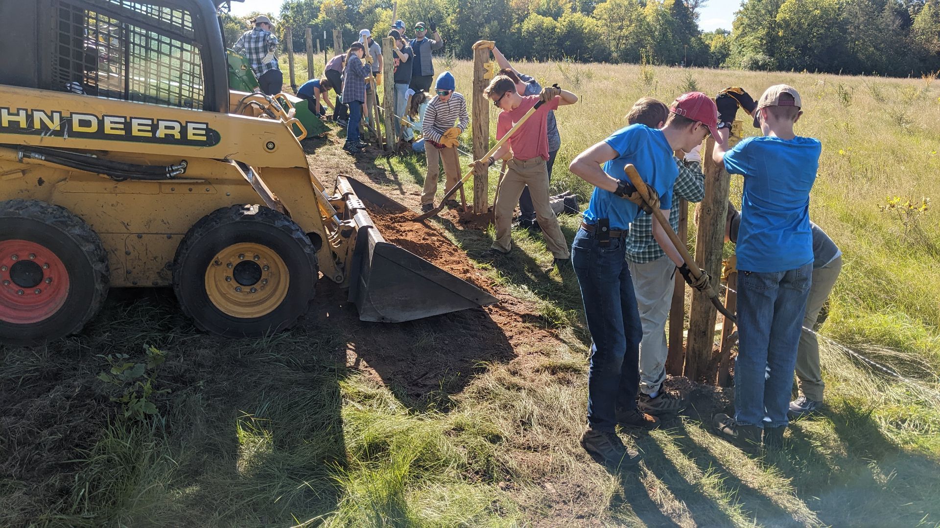 A group of Montessori children are working on a fence in a field.
