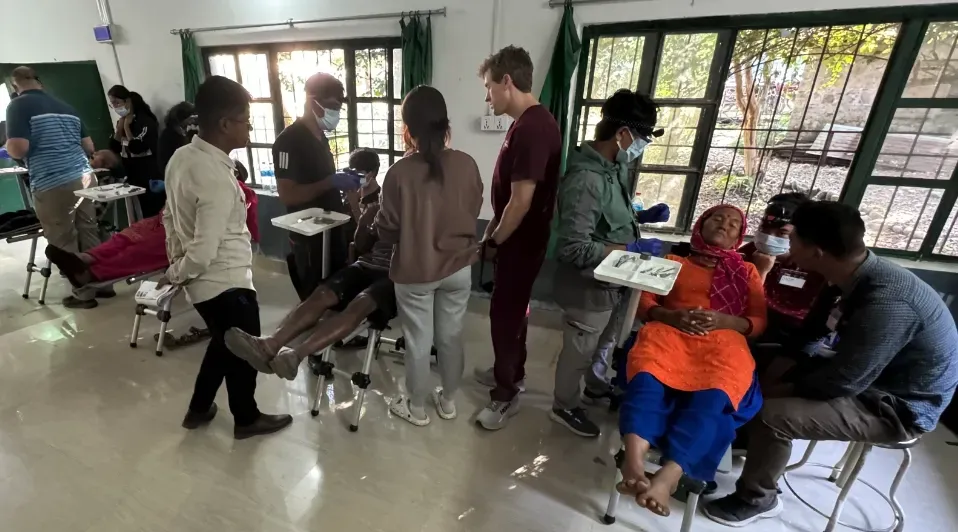 A group of people are standing around a woman sitting in a chair in a room.