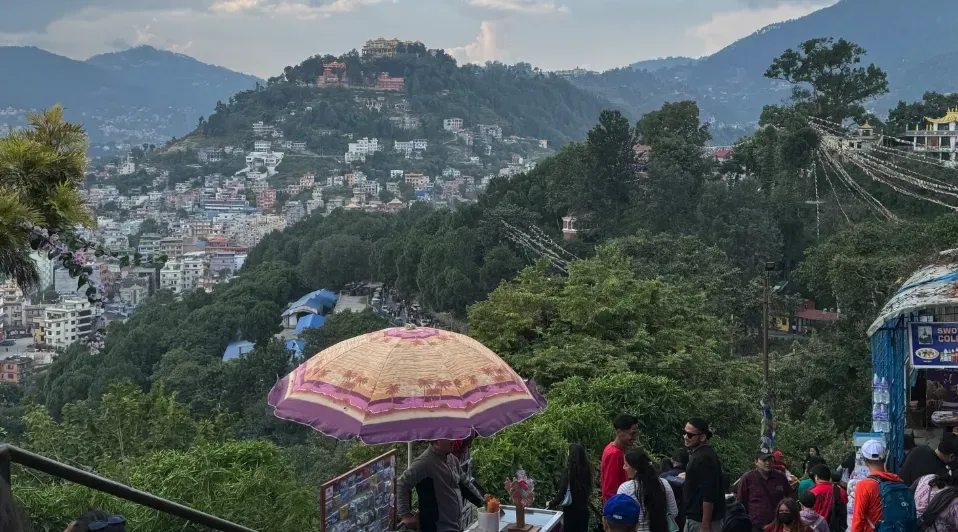 A group of people are standing on top of a hill overlooking a city.