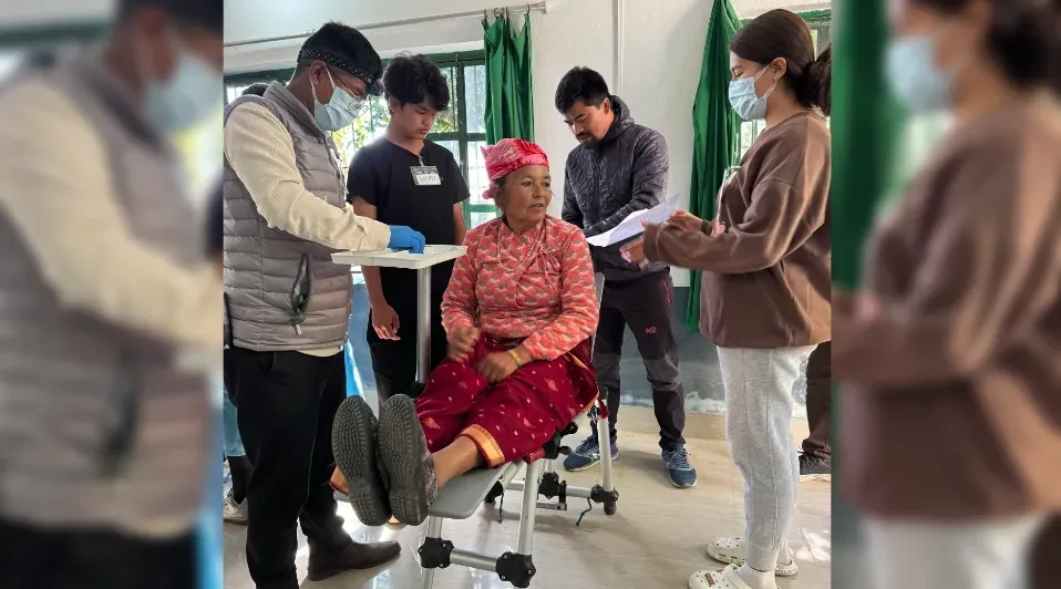 A group of people are standing around a woman in a wheelchair.