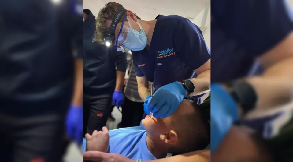A dentist is examining a young boy 's teeth.