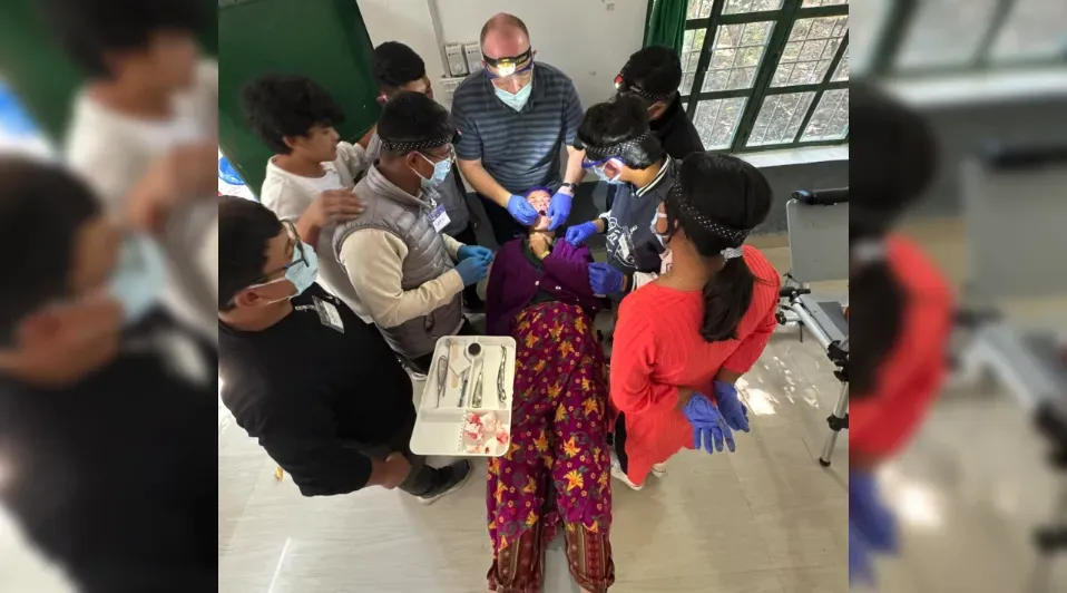 A group of people are standing around a woman laying on the floor.