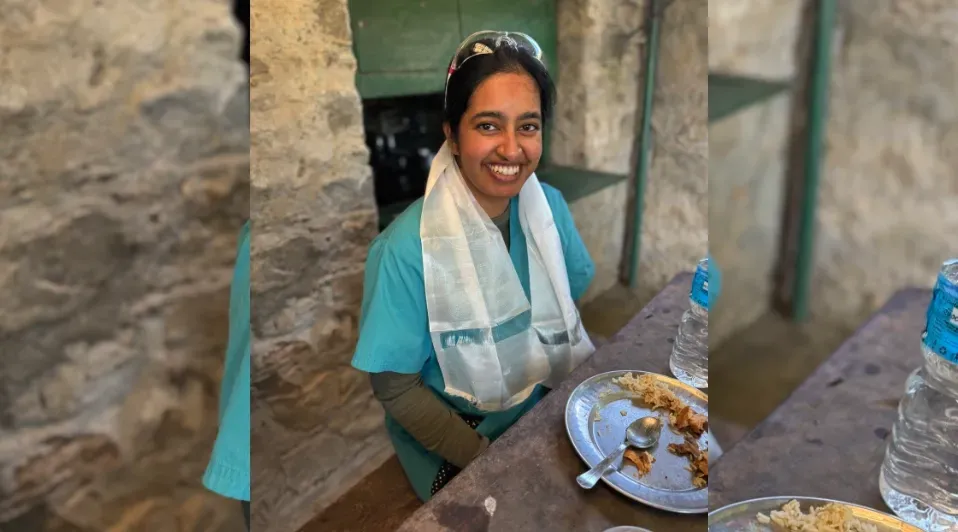 A woman is sitting at a table with a towel around her neck.