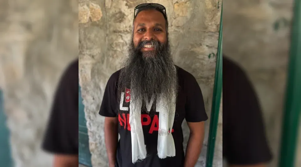 A man with a long beard is wearing a black shirt and sunglasses.