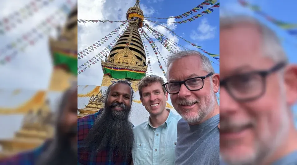 Three men are posing for a picture in front of a temple.