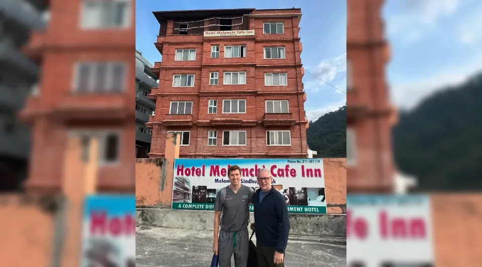 Two men standing in front of a building that says hotel mensch cafe inn