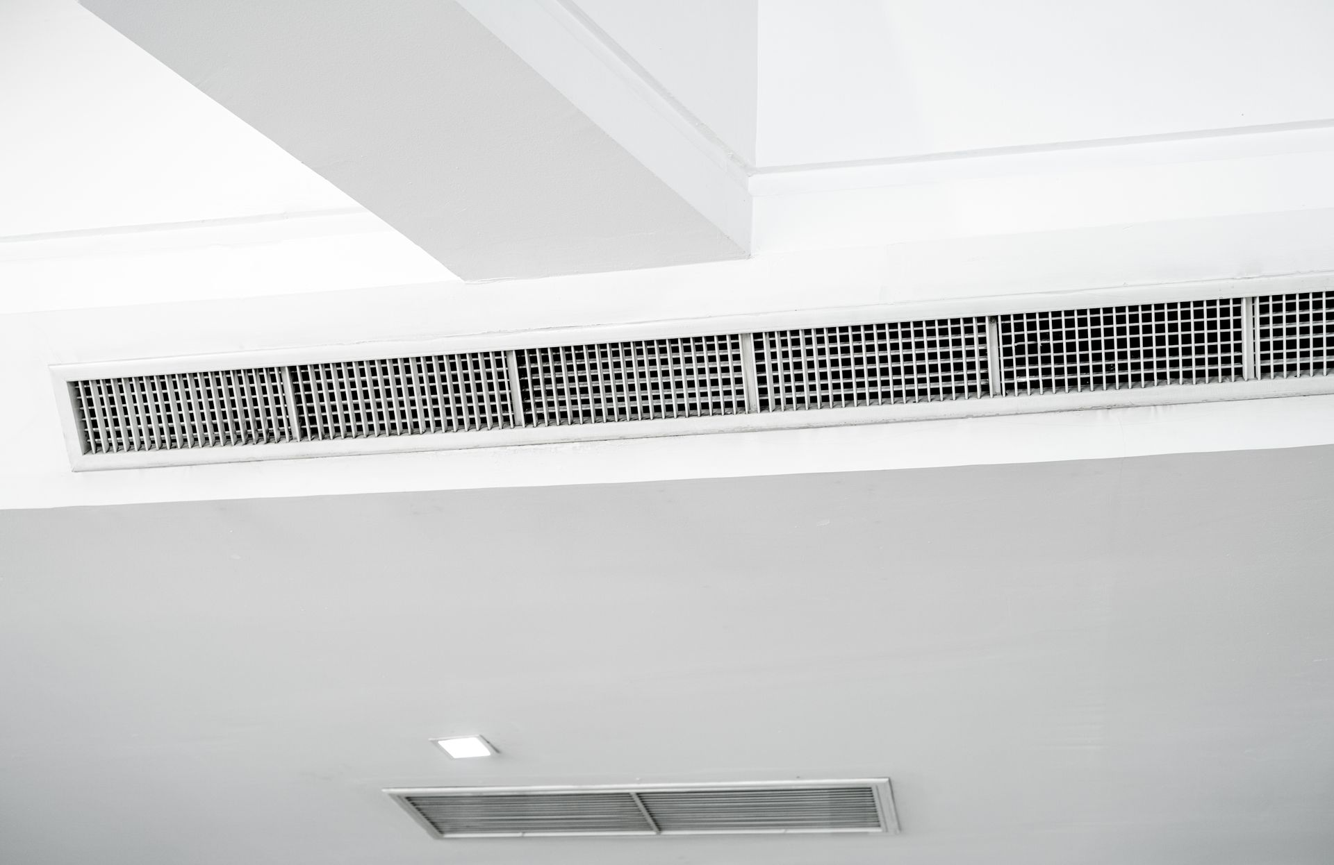 White ceiling with rectangular air vents and a recessed light panel