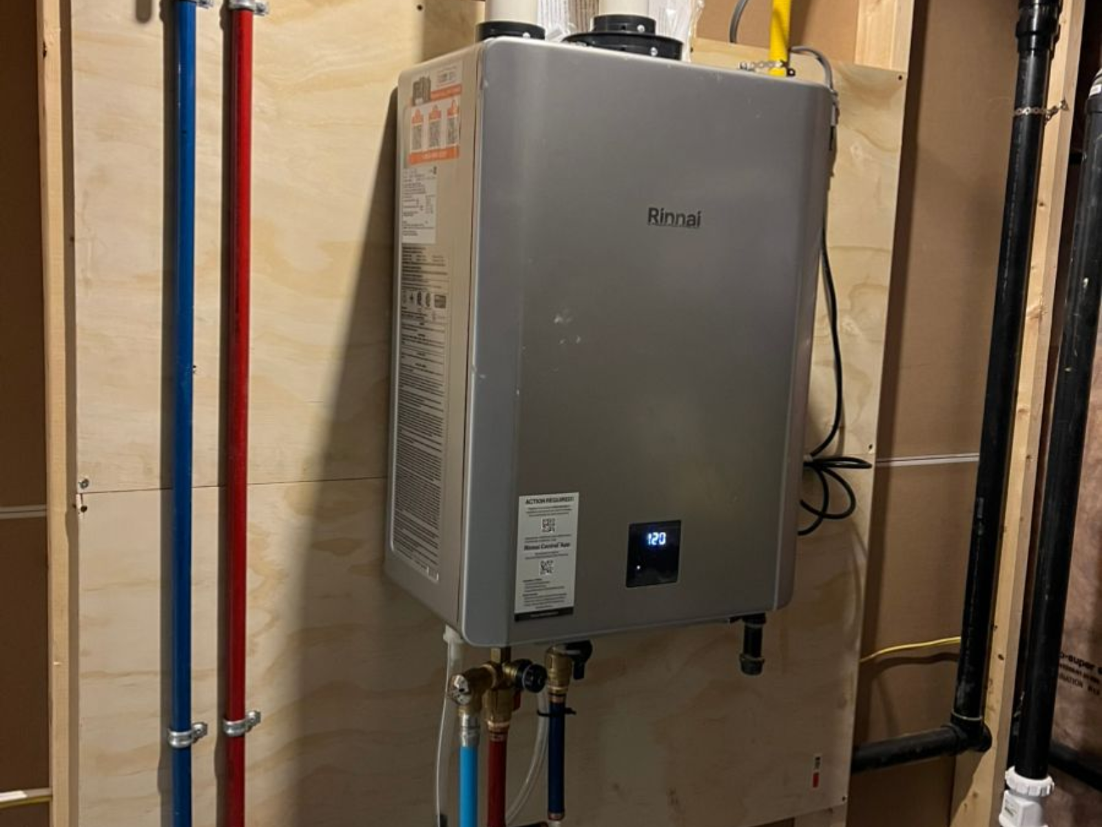 Wall-mounted gray tankless water heater with pipes in a utility room