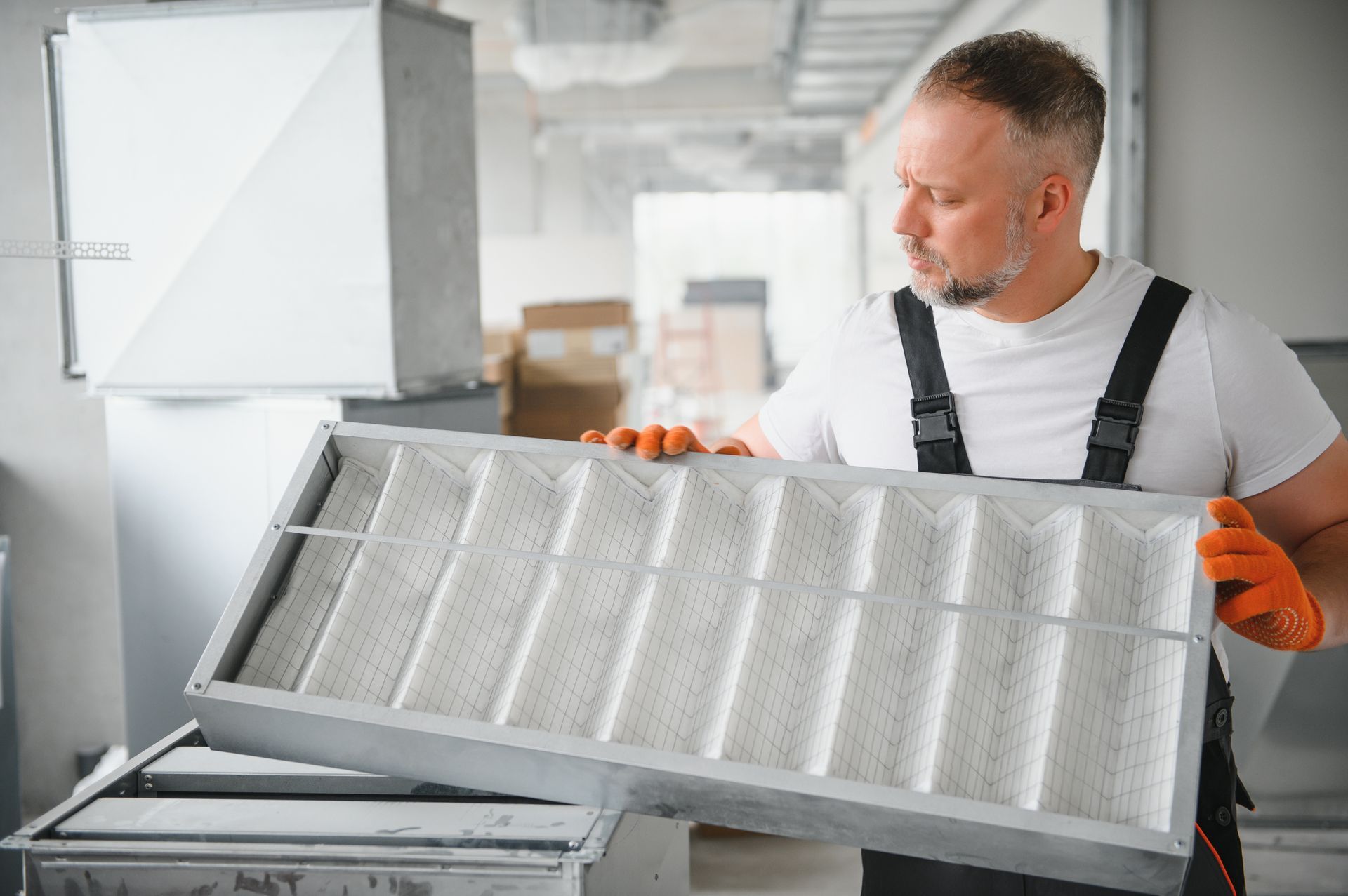 Technician inspecting a large HVAC air filter in a bright utility room