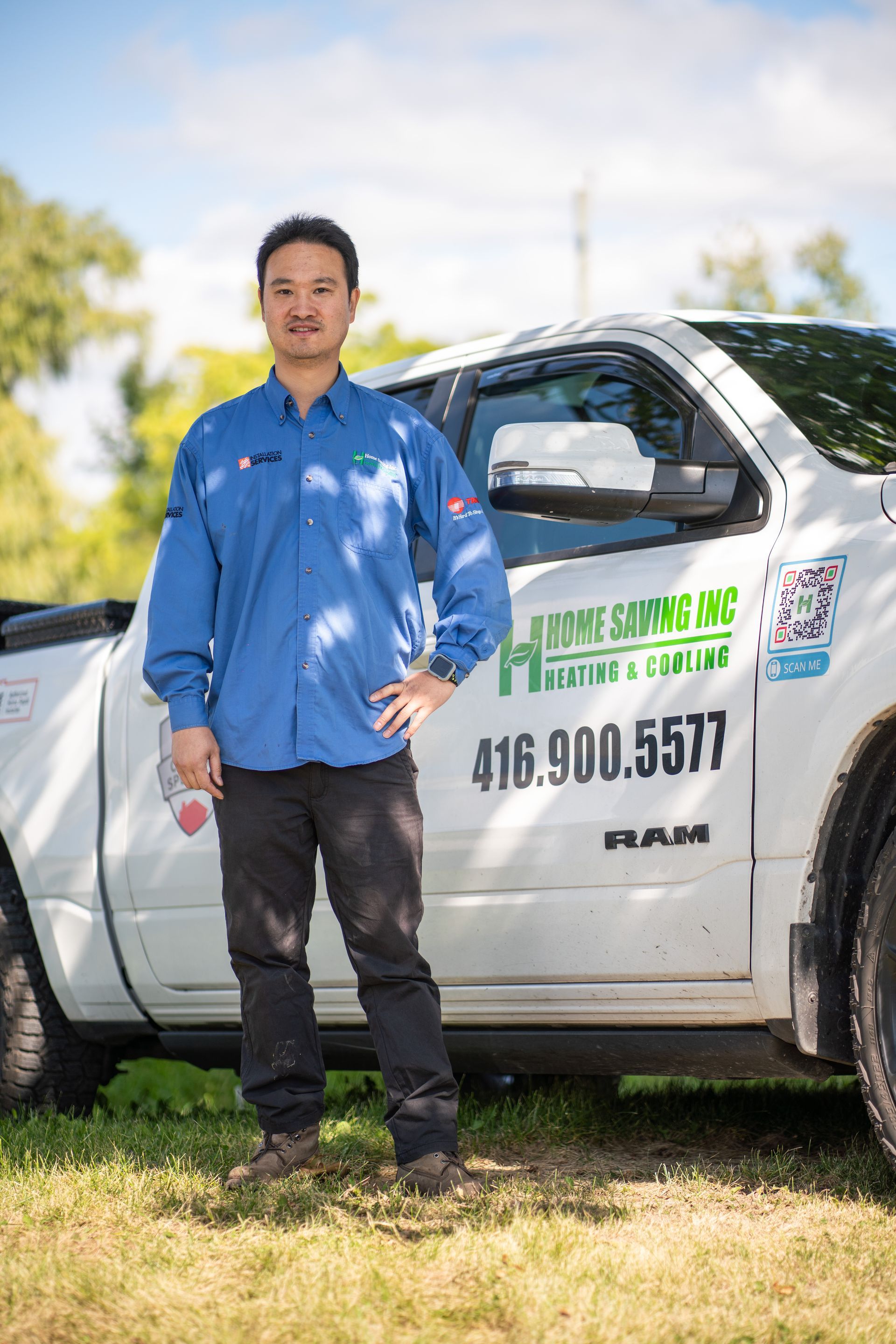 Person standing beside a white service truck with a green company logo and phone number on the door.