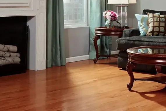 Cozy living room with hardwood floor, fireplace, window, sofa, and side table with flowers