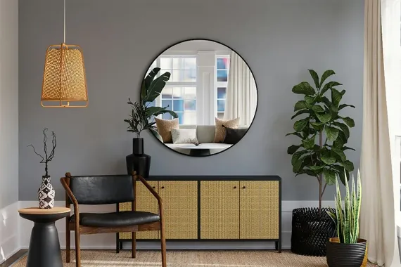 Cozy living room with round mirror, rattan cabinet, chair, and potted plants