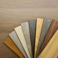 Fan of assorted wood and laminate flooring samples on a wooden surface.