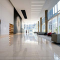 Bright modern lobby with glossy marble floor, tall windows, and minimalist seating area