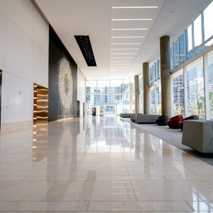 Bright modern lobby with glossy marble floor, tall windows, and minimalist seating area