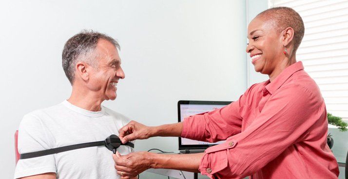 A woman is putting a heart monitor on a man 's chest.