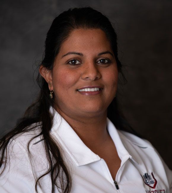 Portrait of a smiling person in a white collared shirt against a dark background