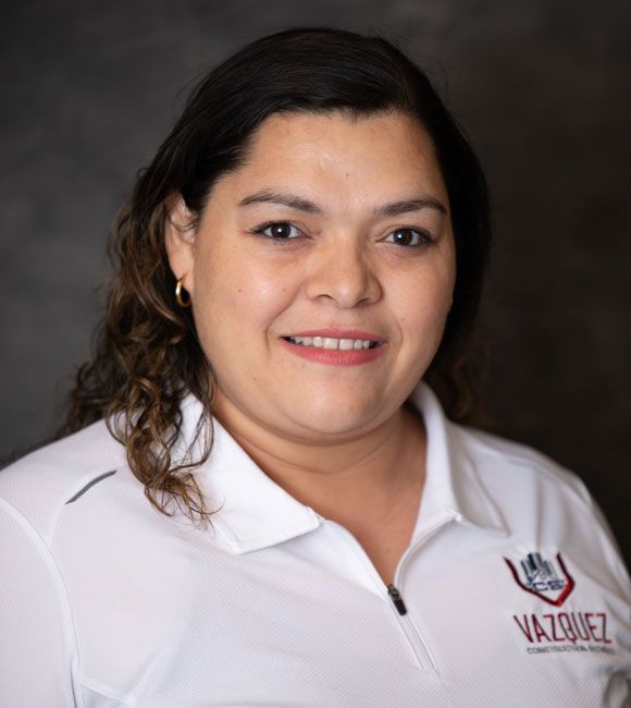 Portrait of a smiling woman in a white polo shirt against a dark background
