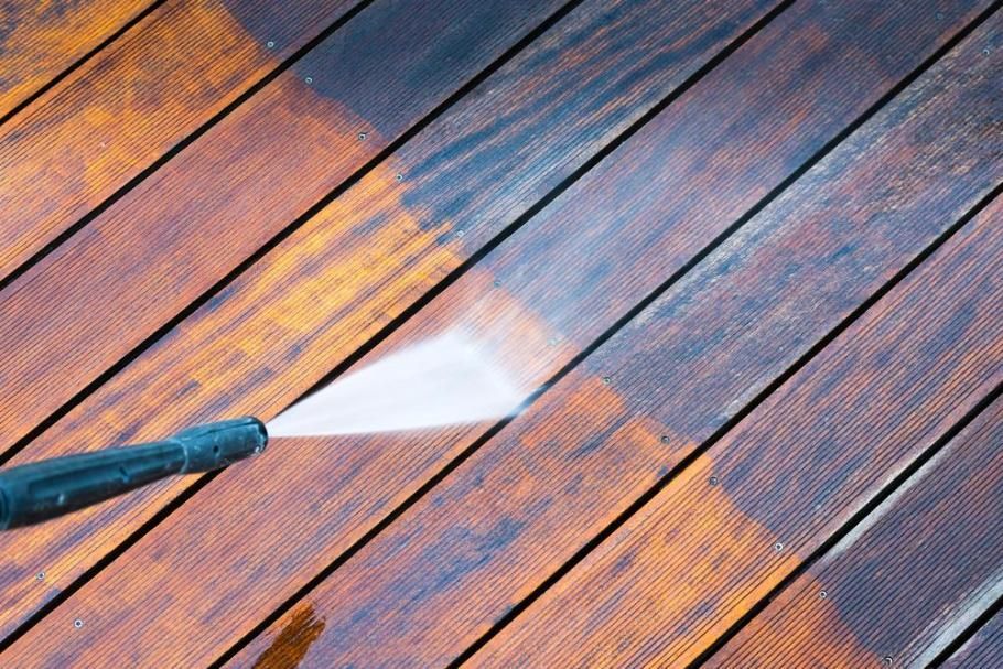 A Person is Using a High Pressure Washer to Clean a Wooden Deck — DJ's Pressure Cleaning In Carruchan, QLD