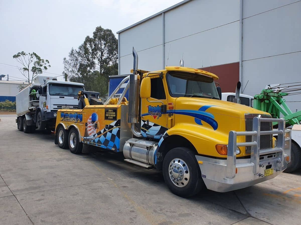 A Yellow Tow Truck Is Parked In Front Of A Building — Newcastle Truck Repairs in Beresfield, NSW