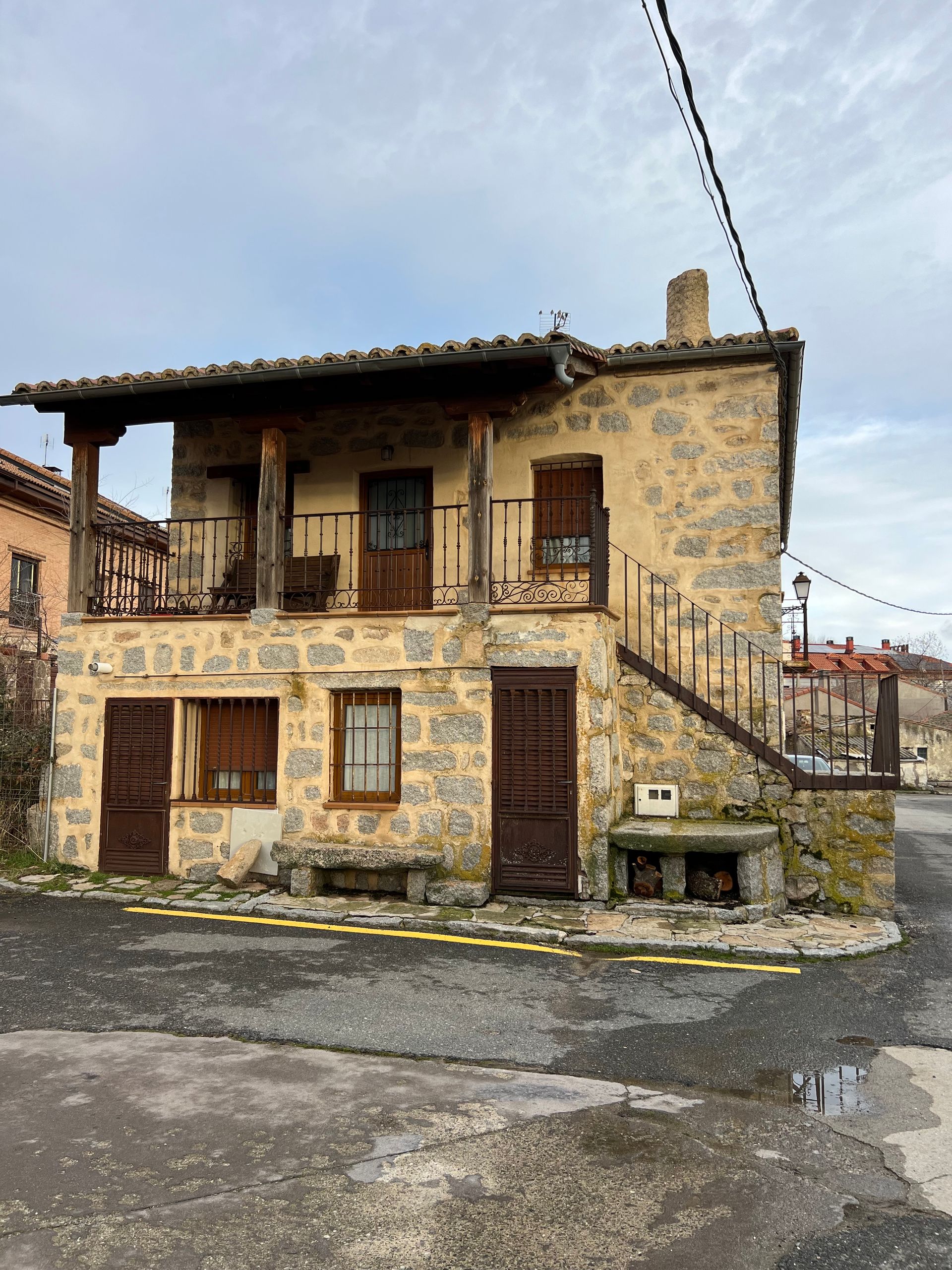 Old stone house with wooden balconies and an exterior staircase on a quiet street