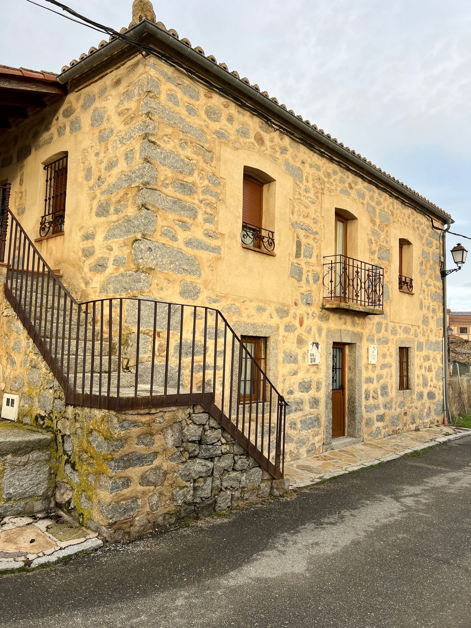 Old stone house with wooden balconies and an exterior staircase on a quiet street
