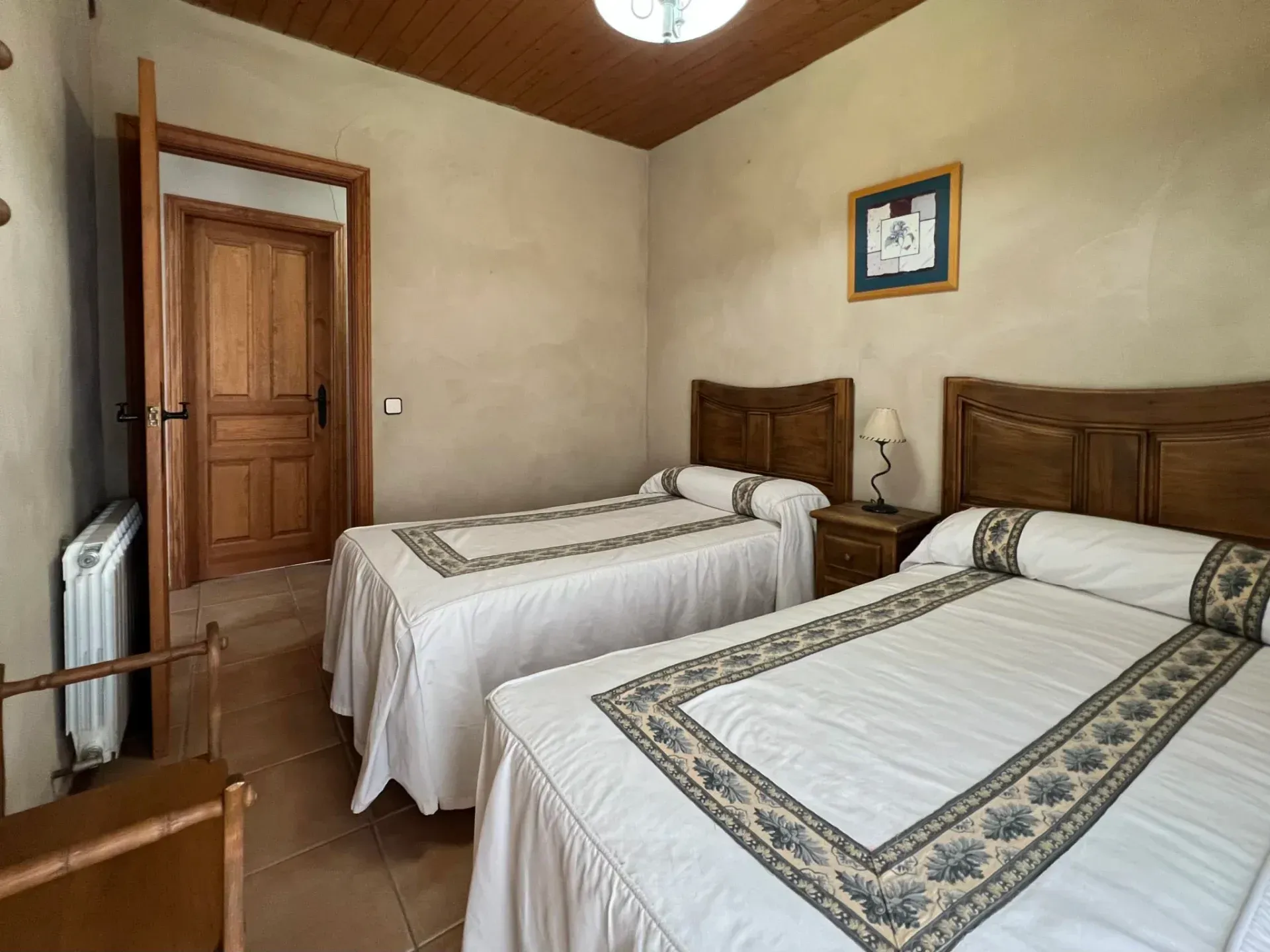 Two twin beds in a beige bedroom with wood accents and a framed picture on the wall.