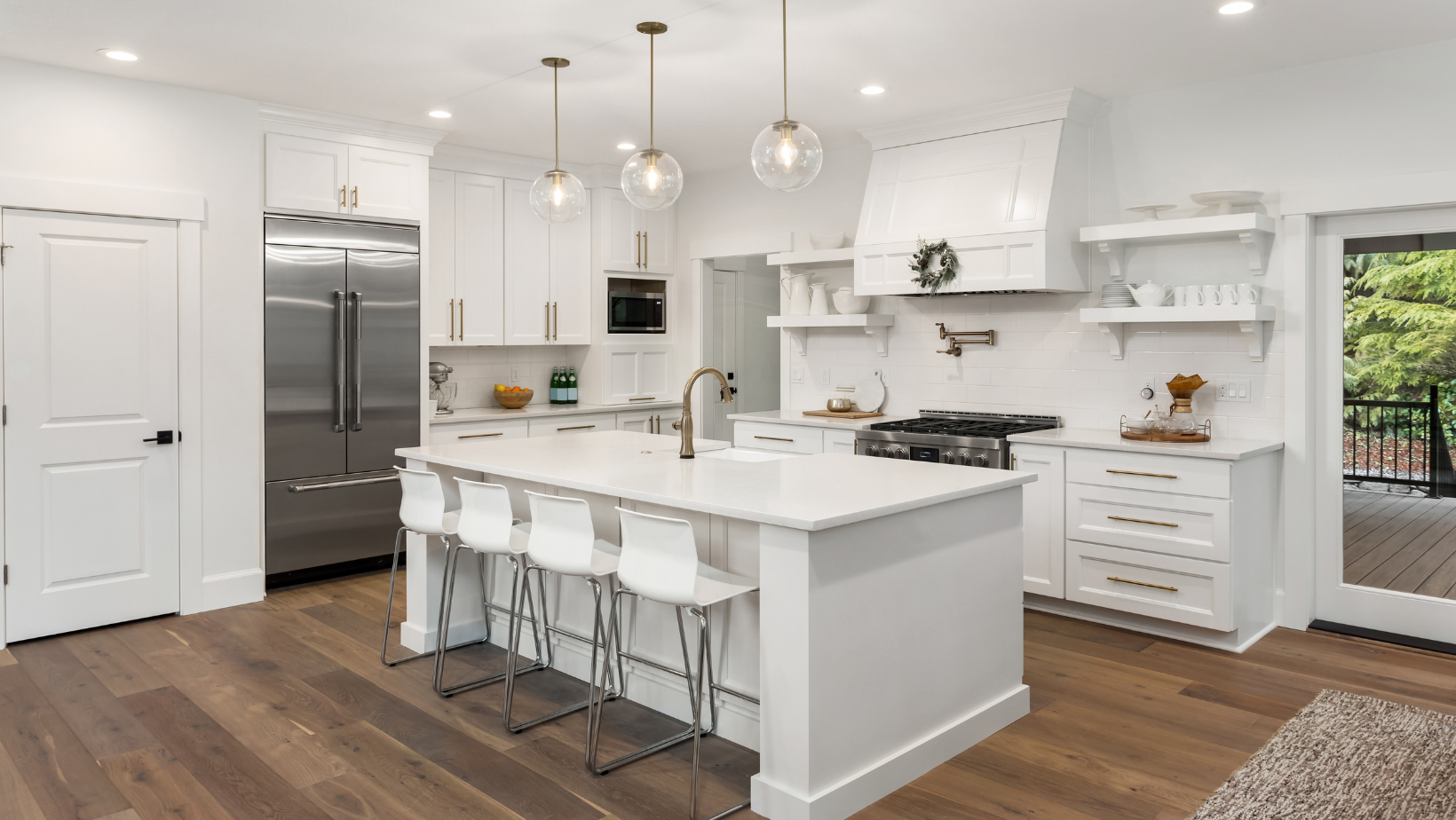 Modern white kitchen with island, stainless steel appliances, and hardwood floors.