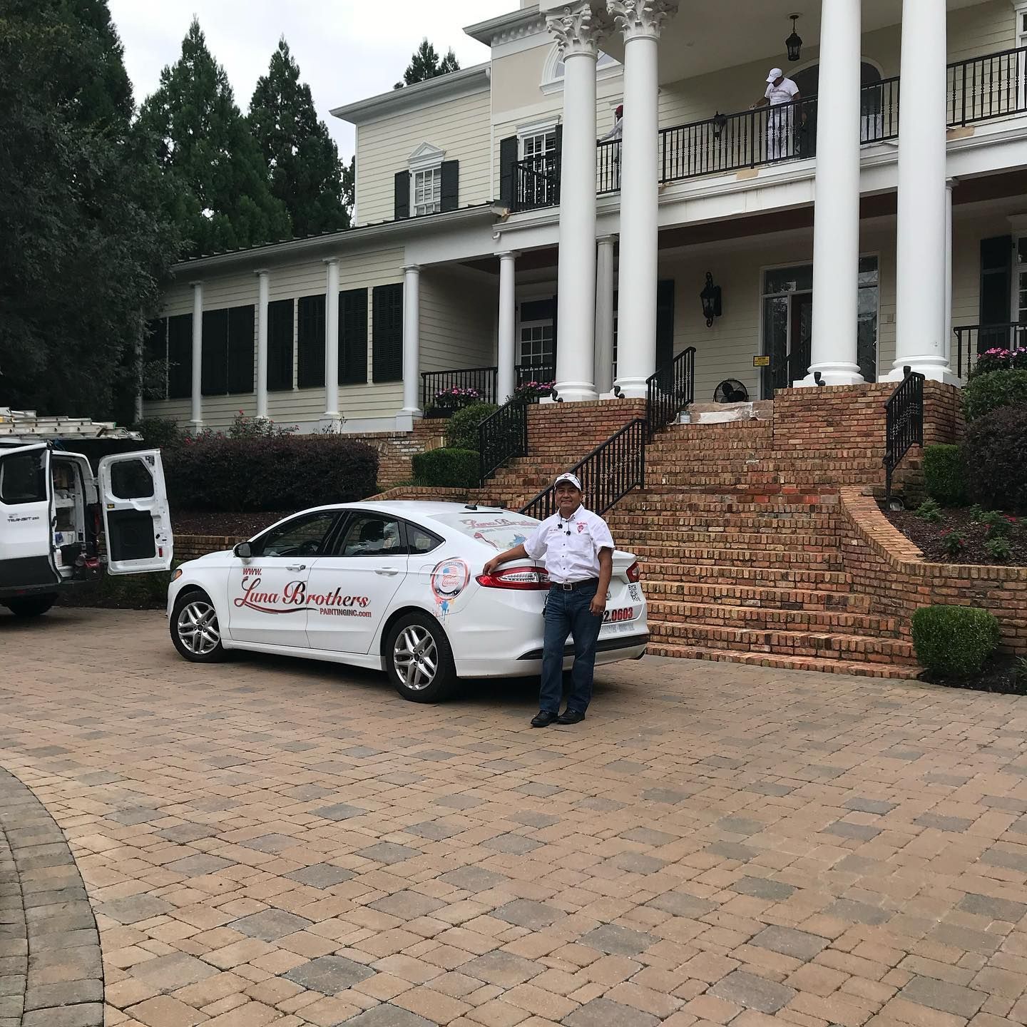 A man stands in front of a white car that says home master