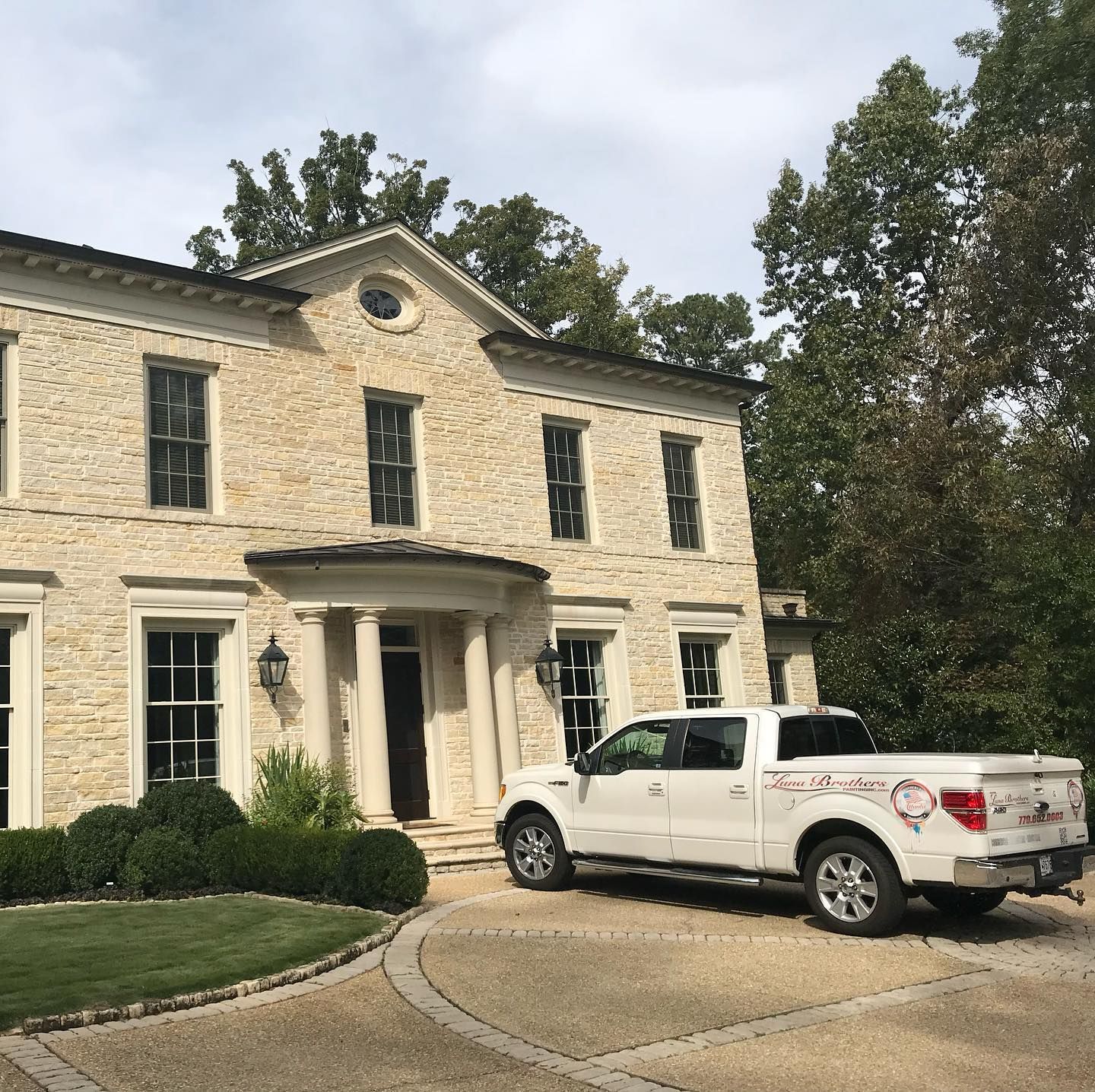 A white truck is parked in front of a large brick building