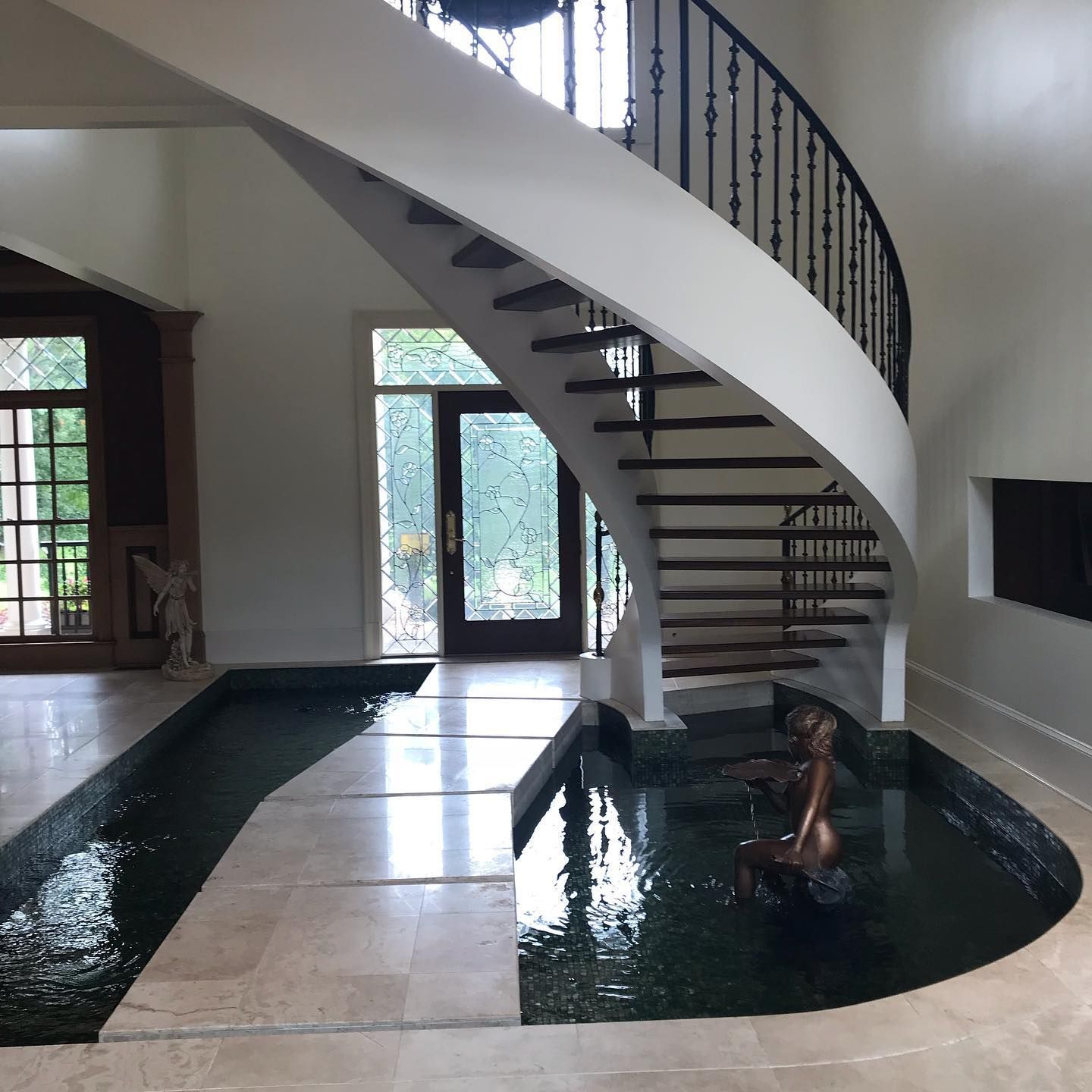 A spiral staircase in a house with a pond underneath it