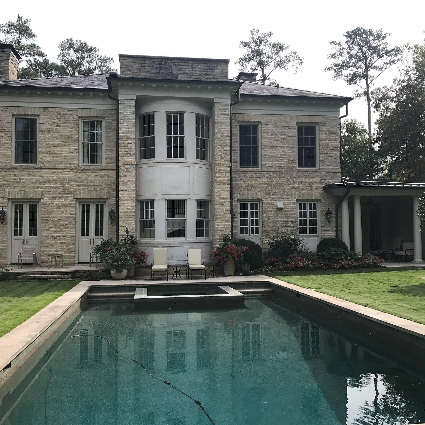 A large brick house with a large swimming pool in front of it