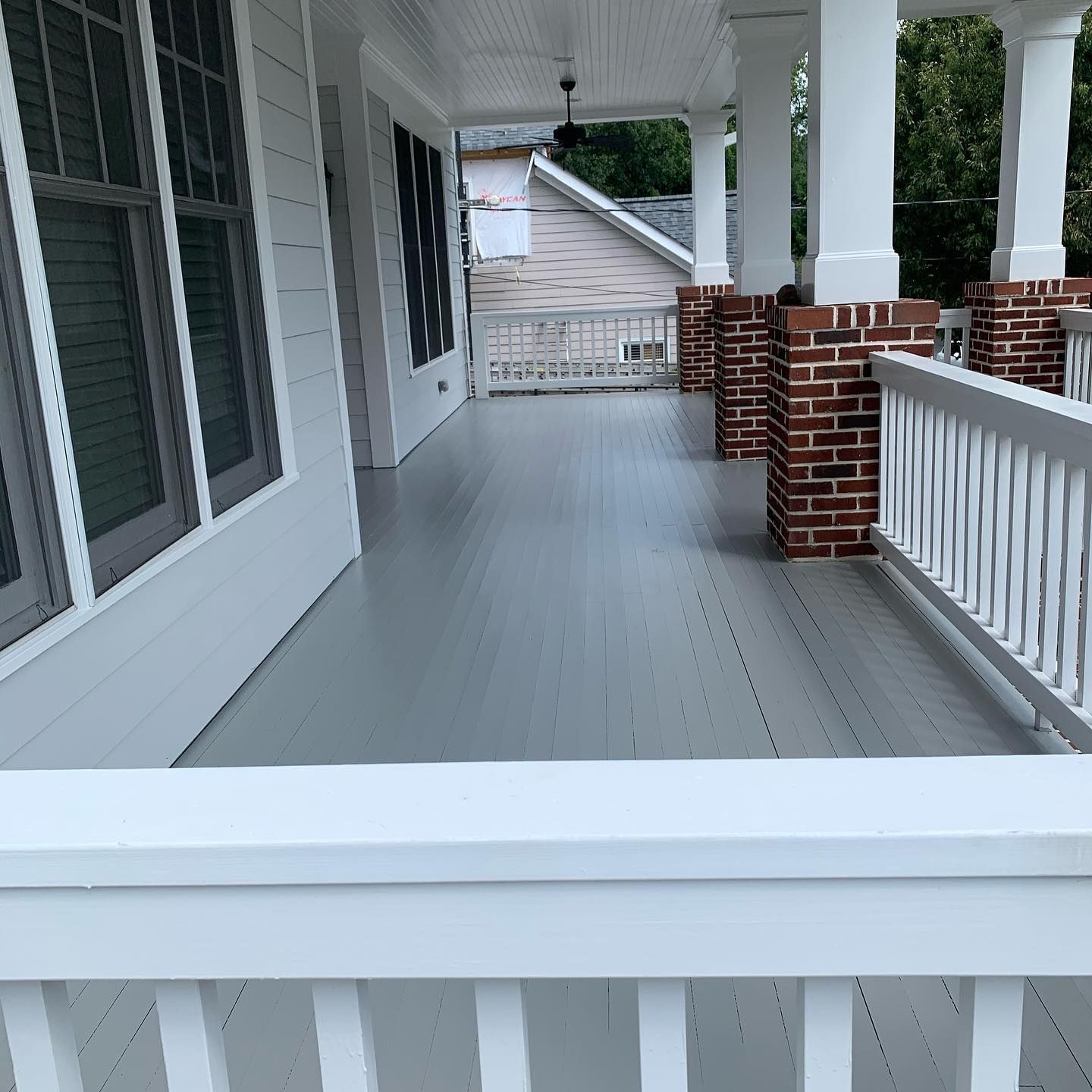 A porch with a white railing and brick pillars