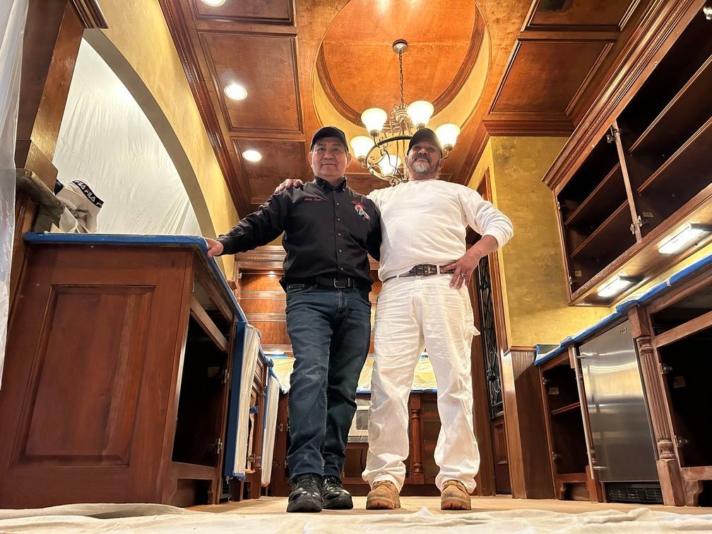 Two men are standing next to each other in a kitchen.
