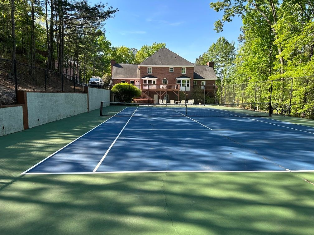A tennis court with a large house in the background
