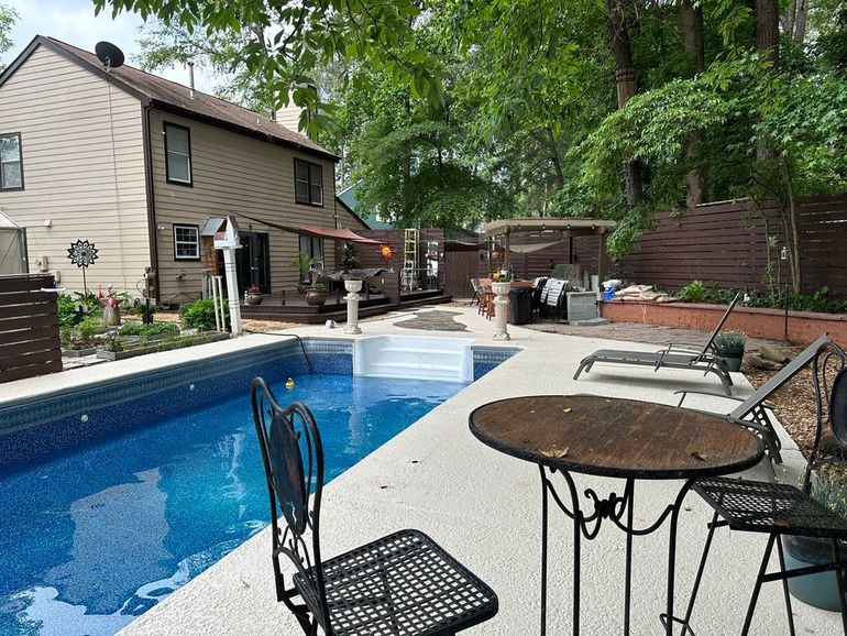 A table and chairs are sitting next to a large swimming pool.