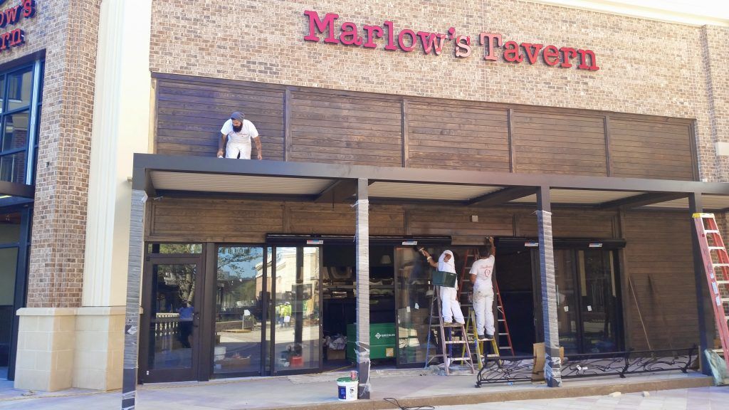 A group of people are painting the front of a building that says marlow 's tavern