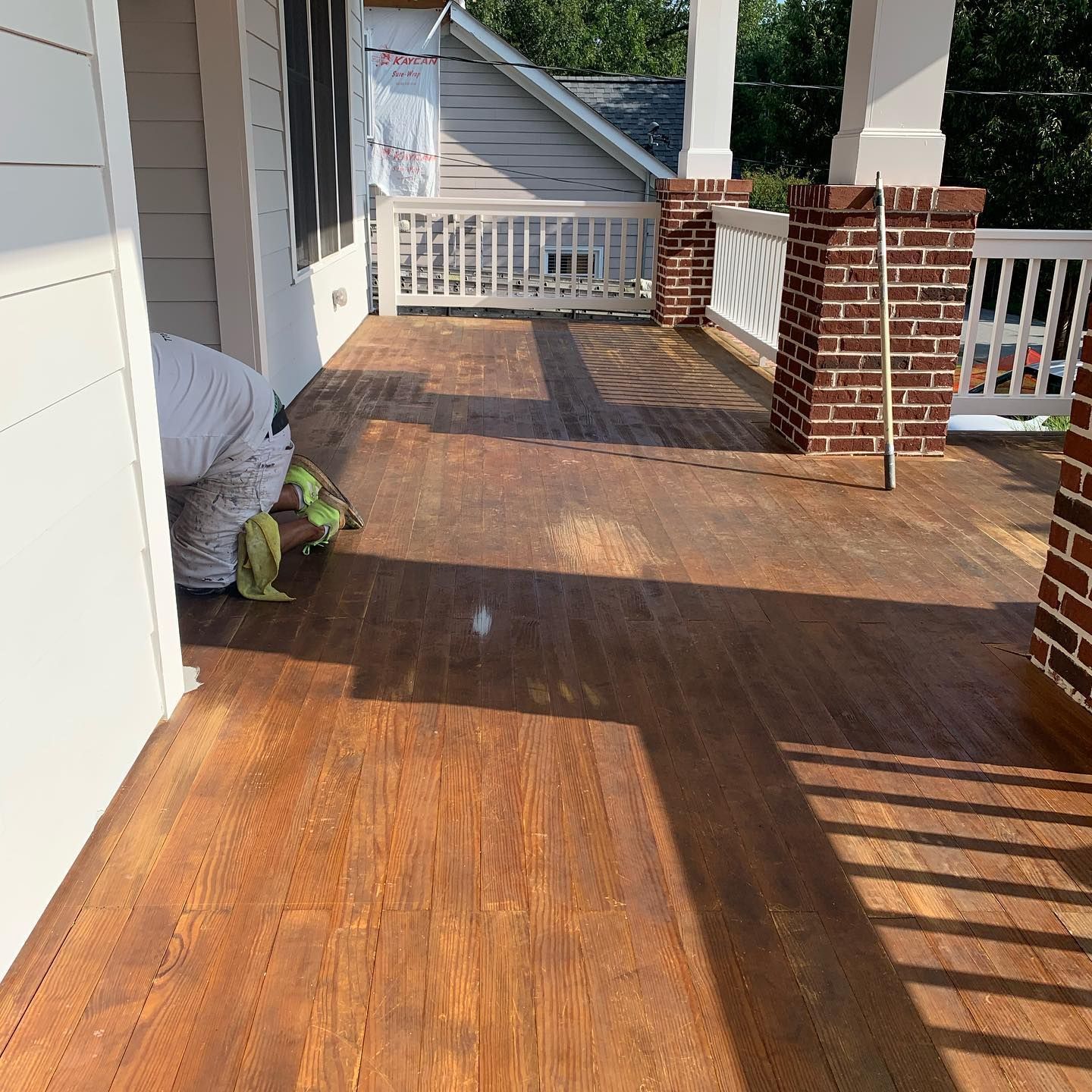 A porch with a wooden floor and brick pillars
