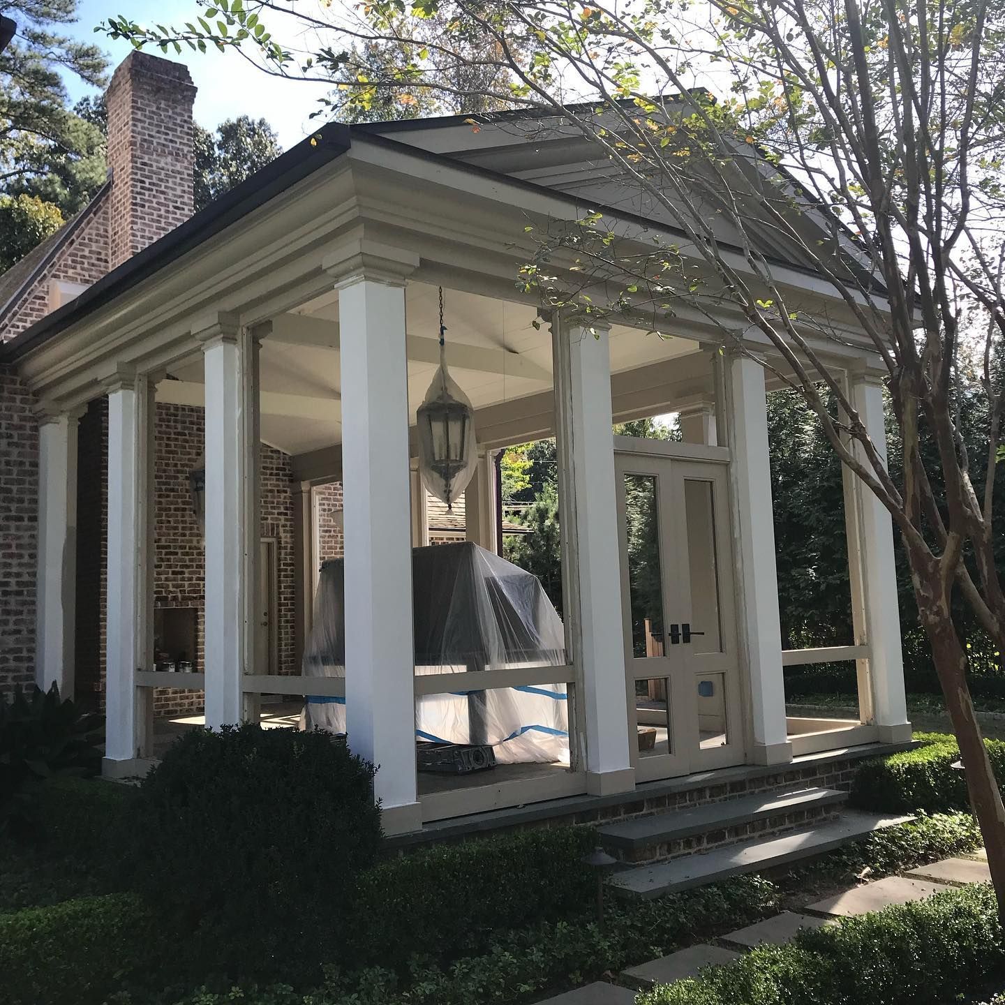 A brick house with a screened in porch with white columns