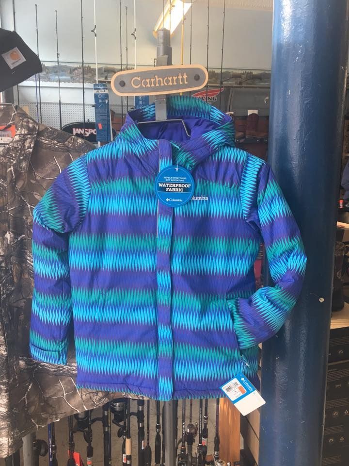 A purple and blue striped jacket is hanging on a pole in a store