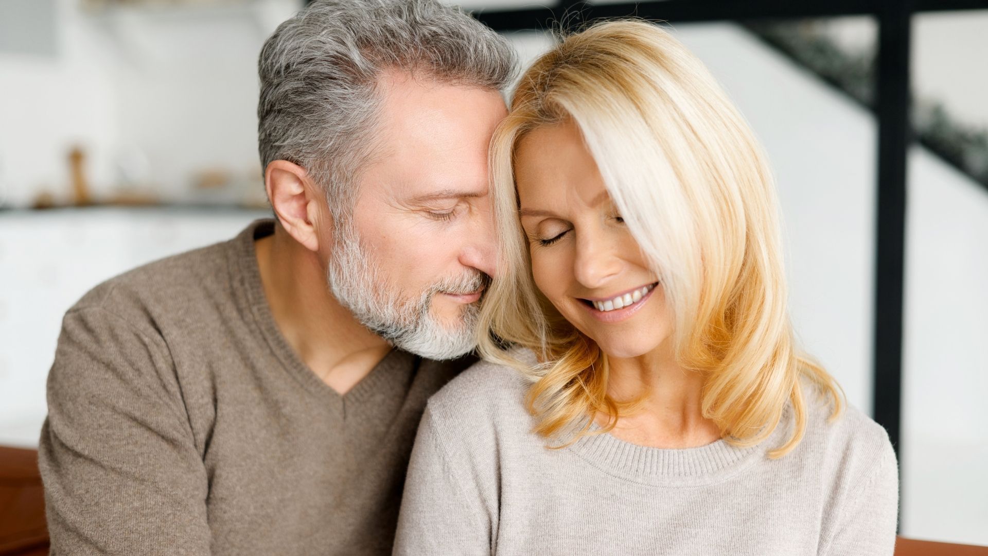 Two people smiling closely together in a bright indoor setting