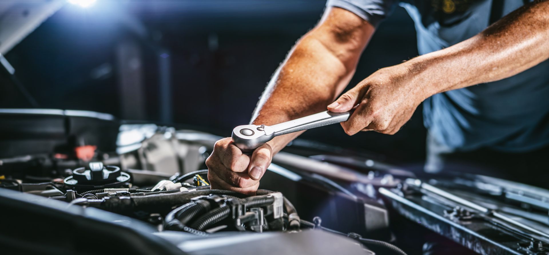 Mechanic performing Volvo auto service on an engine using a ratchet for precise car repairs.