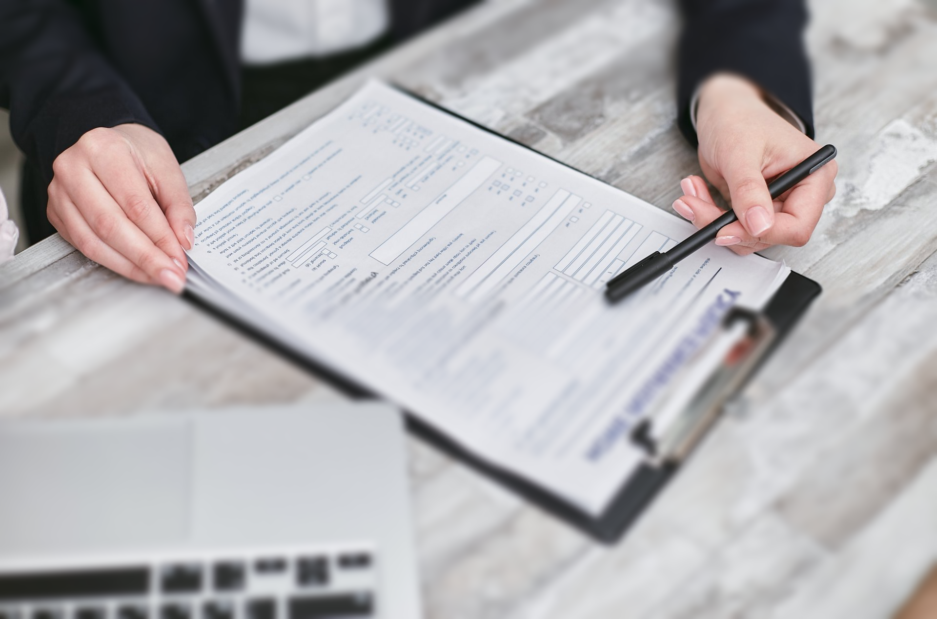 A woman is signing a document on a clipboard with a pen.