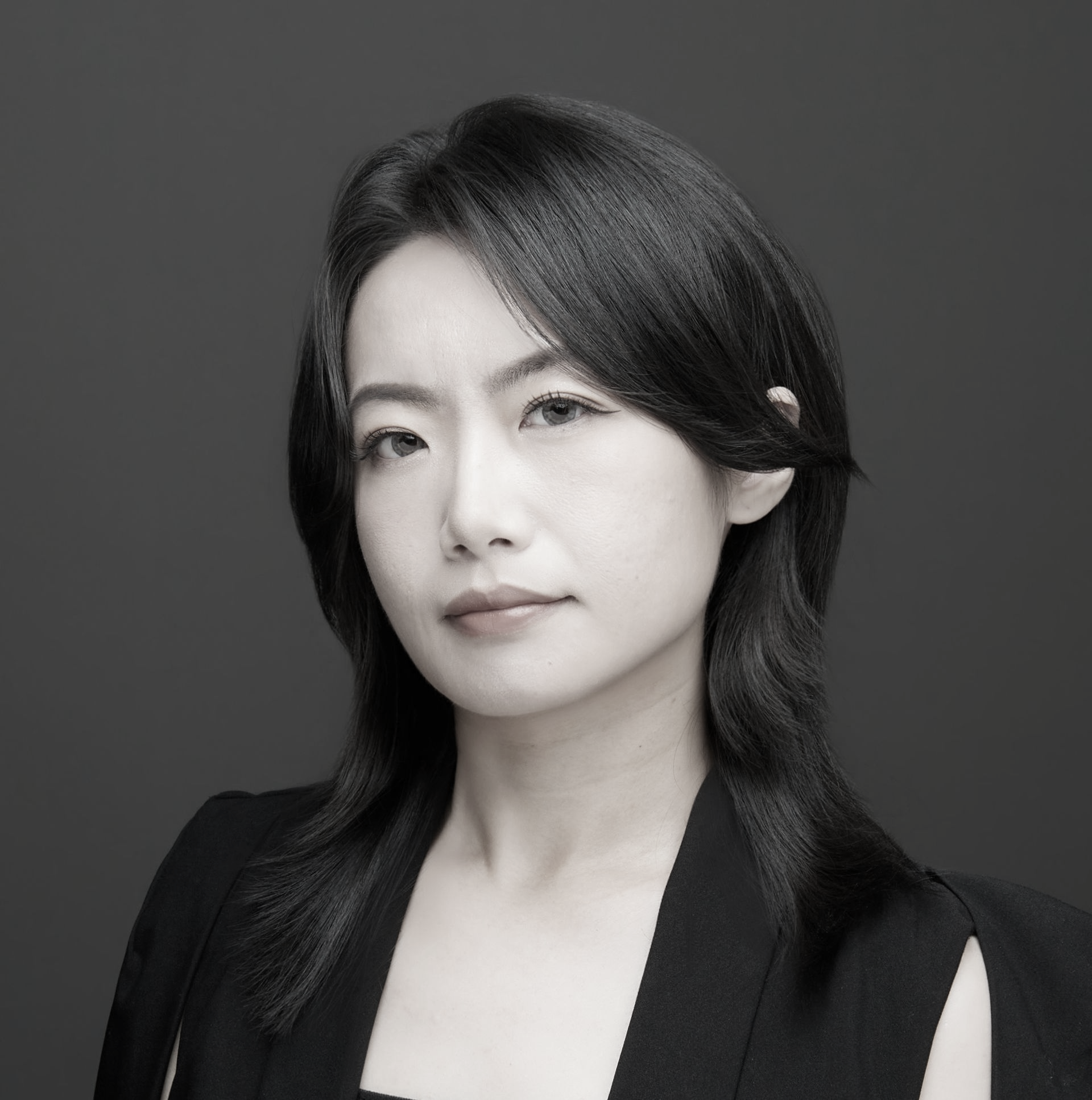 一張黑白照片中，一位穿著西裝和白襯衫的女人微笑著。