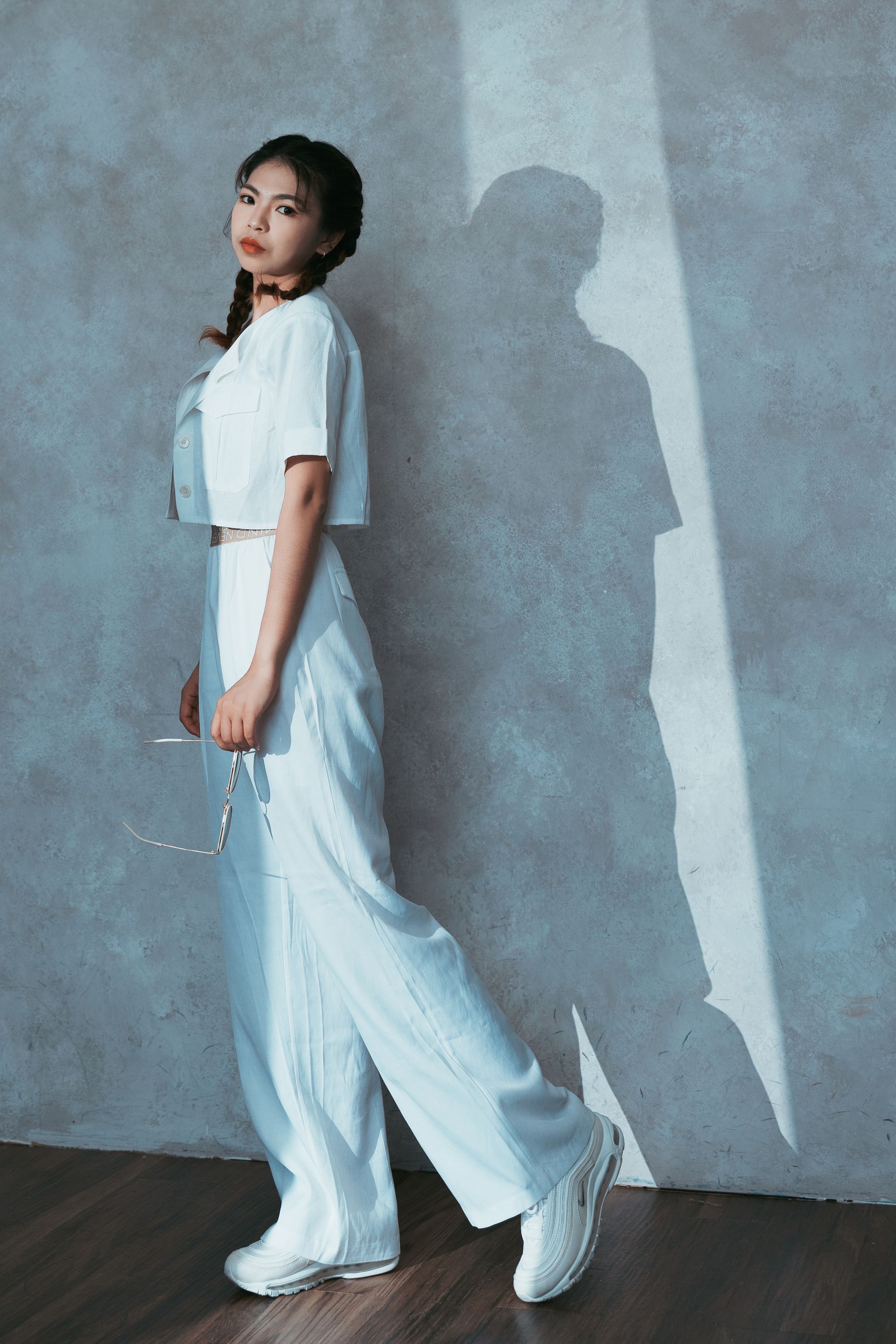 一個穿著白色衣服的女人站在牆前。