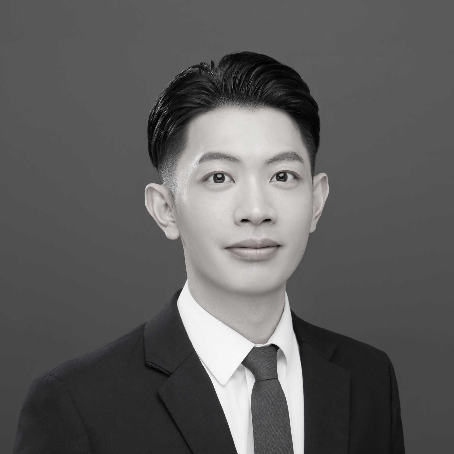 黑白照片中，一名身穿白色夾克的女子微笑著。