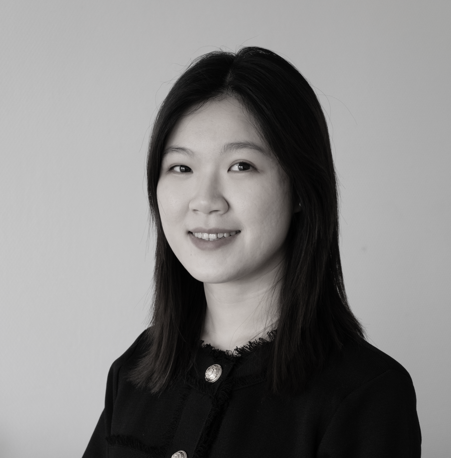 一張黑白照片中，一位穿著西裝和白襯衫的女人微笑著。